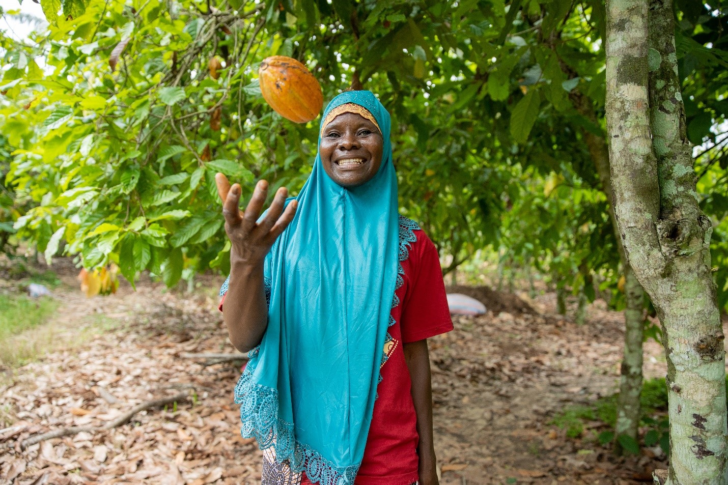 A woman cocoa farmer smiling and handling a cacao pod