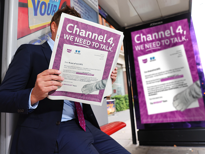 A man sitting at a bus stop, reading Whiska's open letter to Channel 4.
