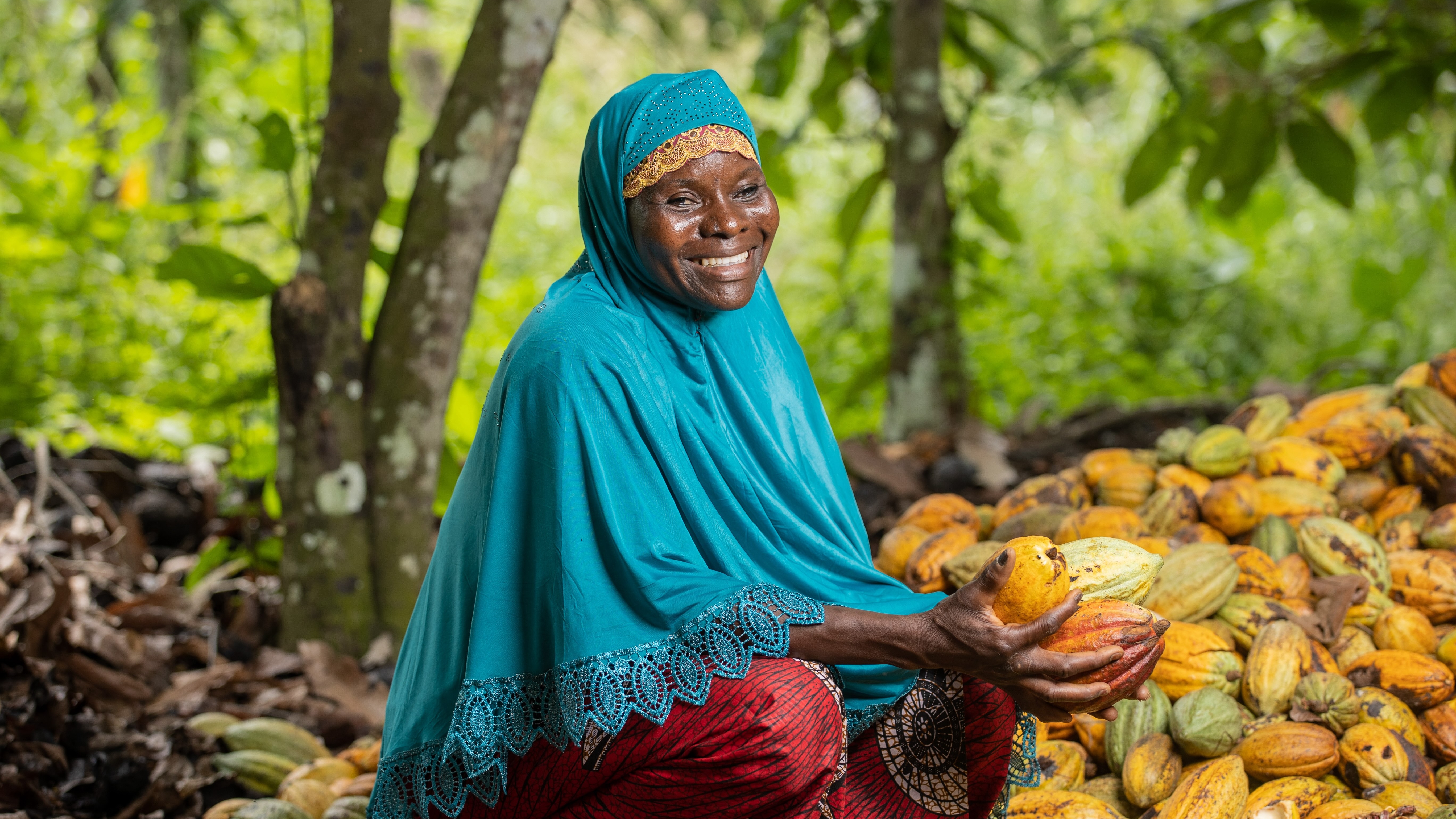 A Woman for Change participant sits with cocoa pods
