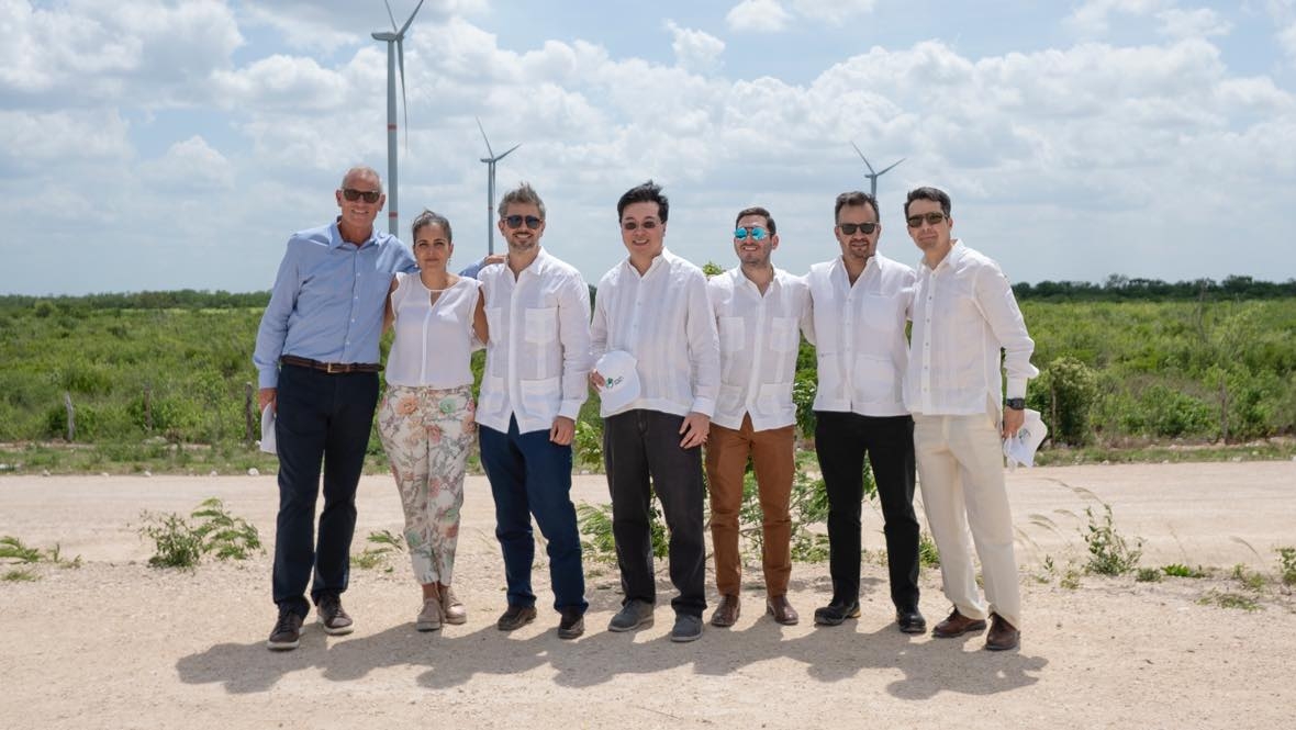 A group of people with a wind turbine behind