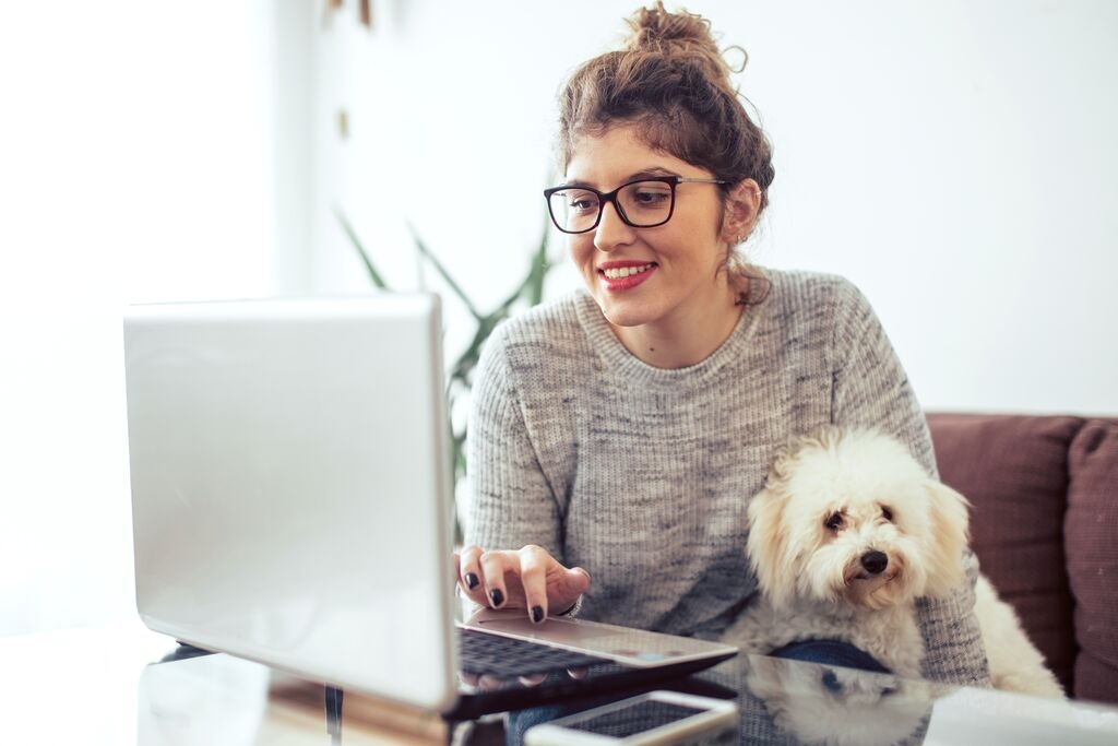 Woman on her computer accompanied by her dog.