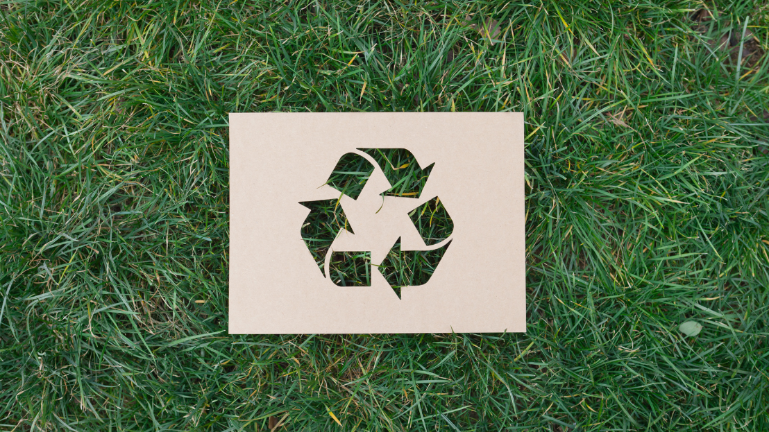 Reduce, reuse, recycle symbol on top of grass