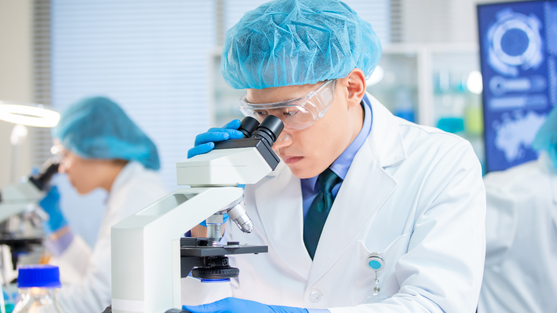 Man looking into a microscope in a lab