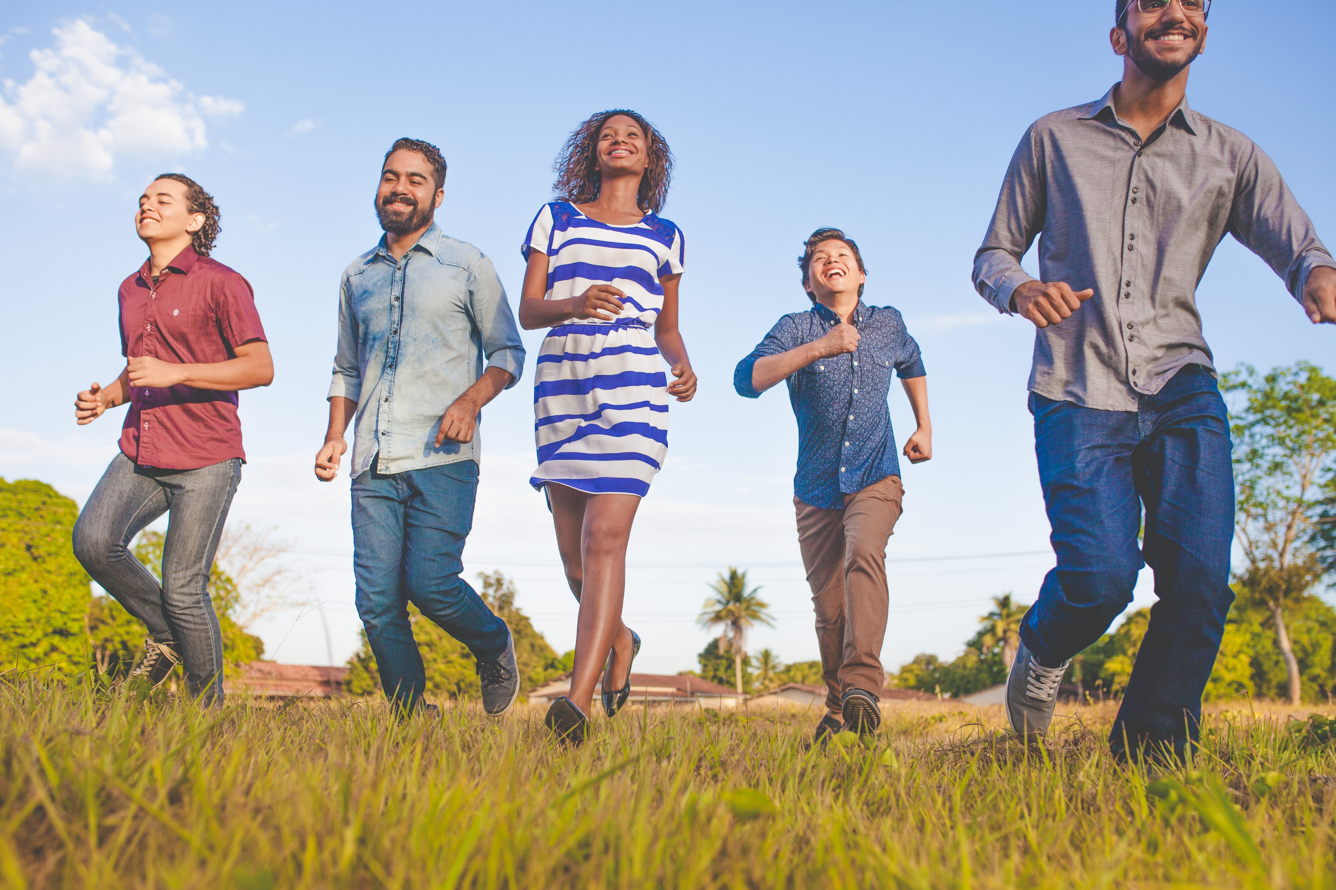 Five happy people running in a field toward the camera