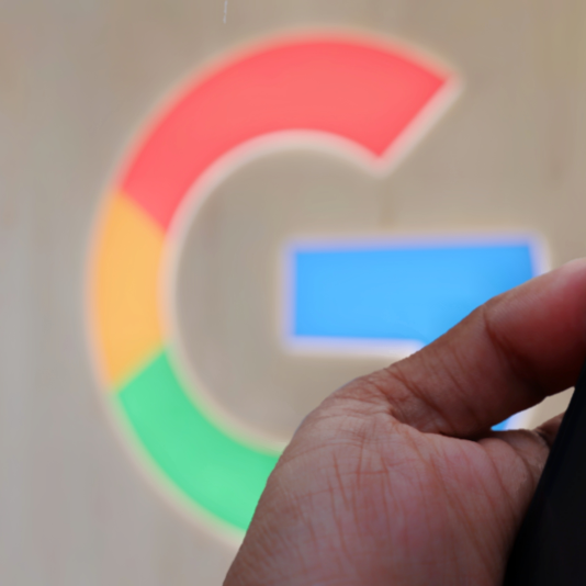 The Google logo and a hand holding a smartphone with Google Gemini on screen.
