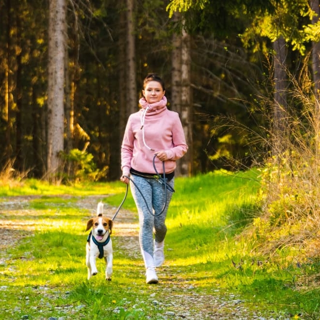 Woman trail running with a dog 