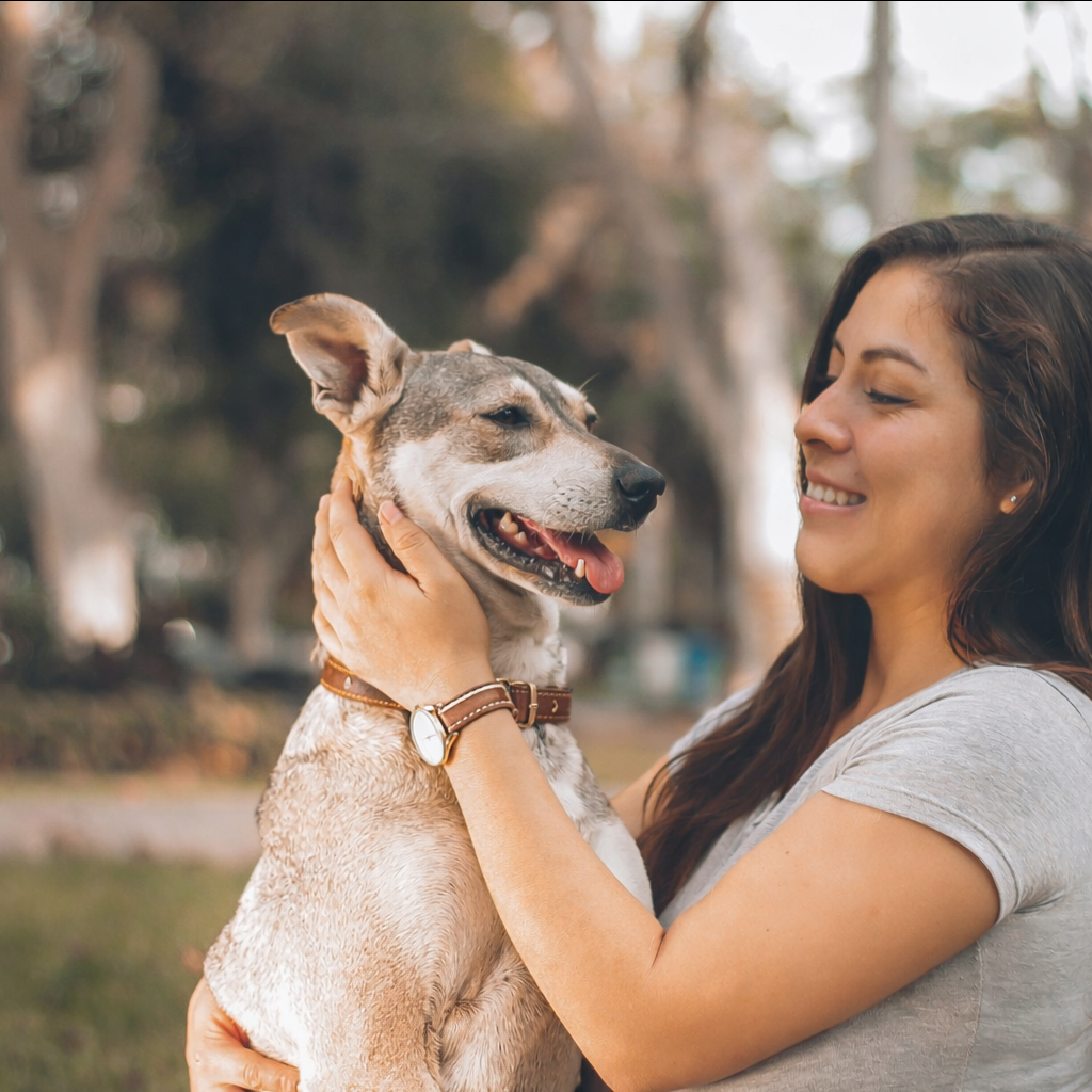 A woman lovingly holding a dog outside in the grass.