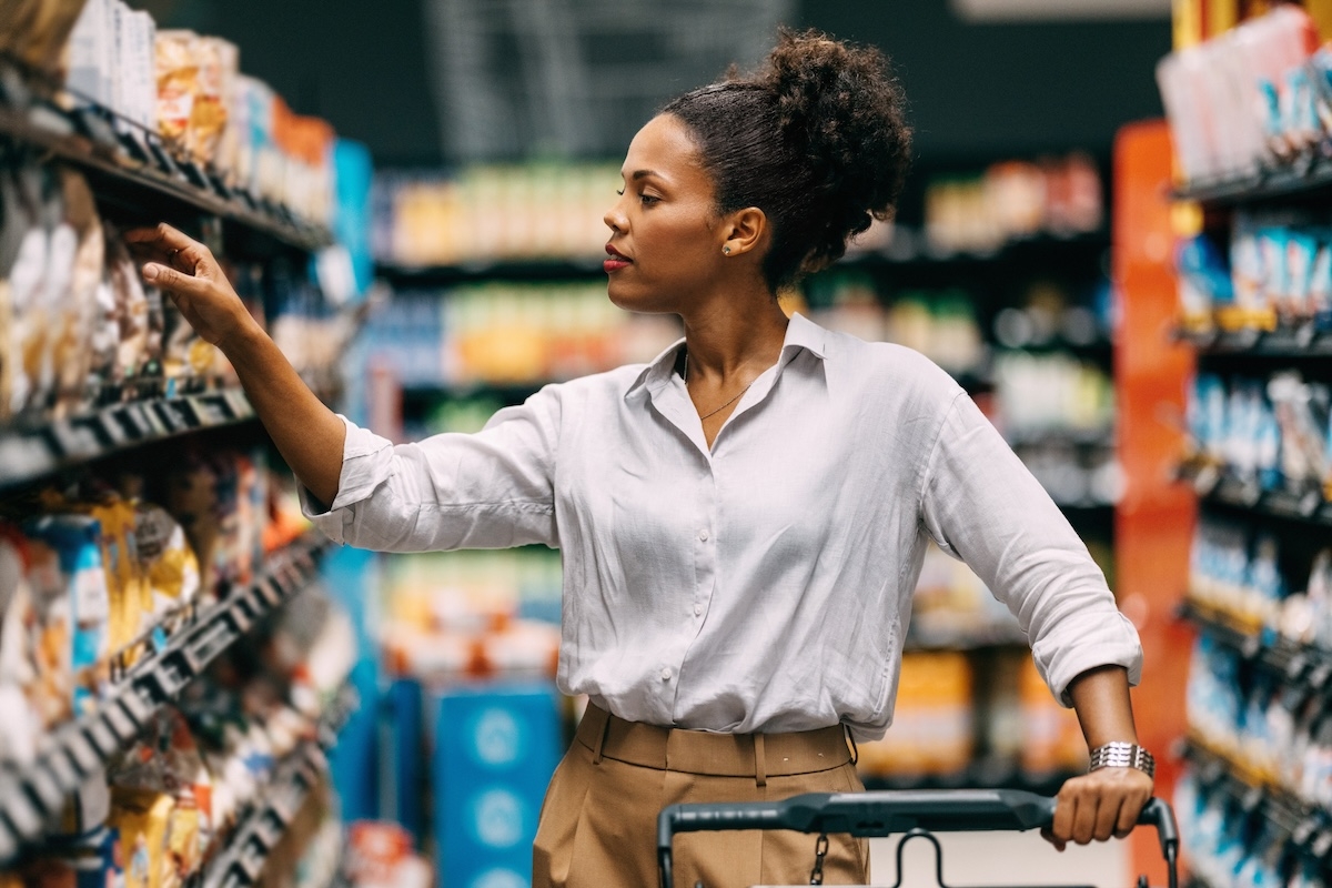 A woman looks at items in a grocery store aisle.