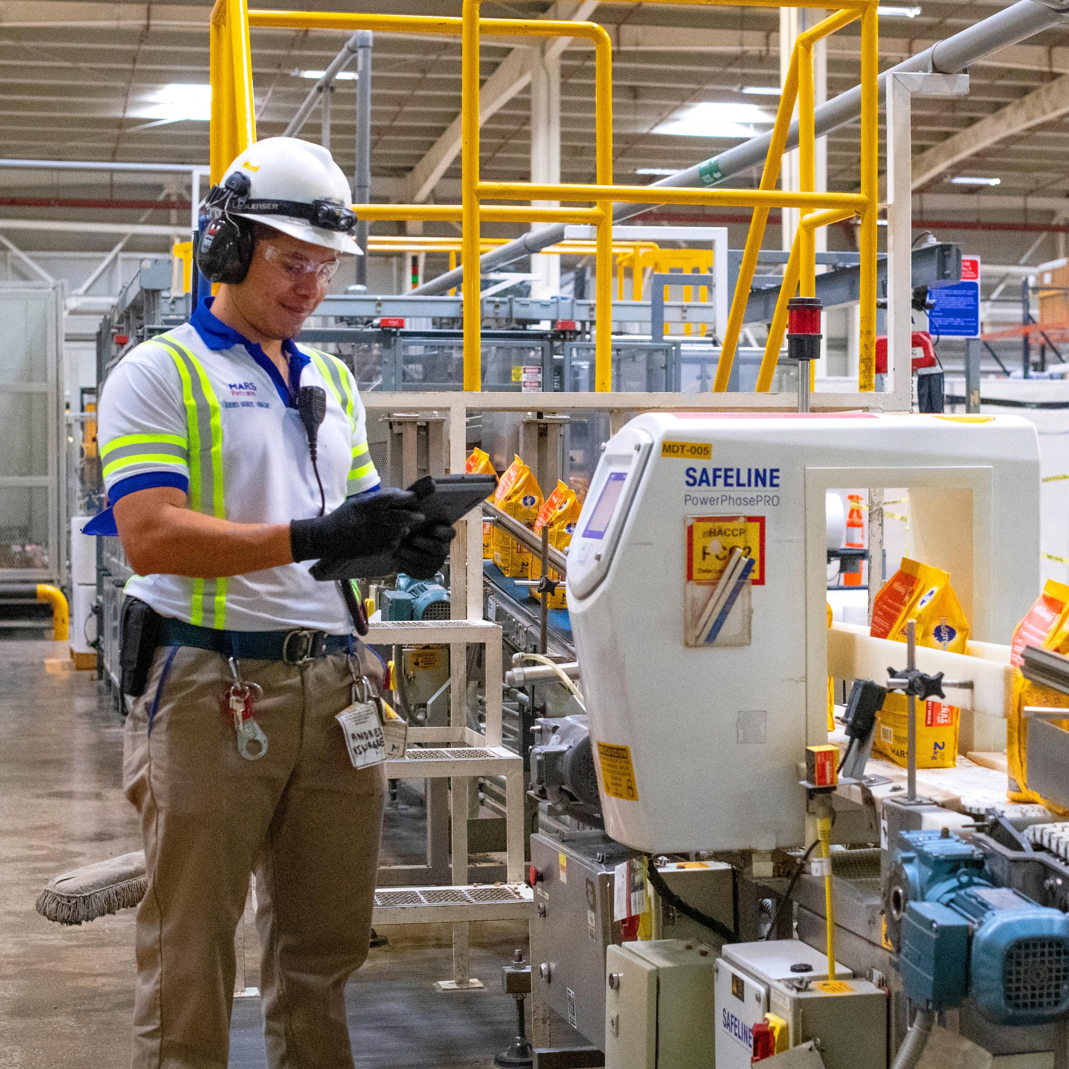 Man stood before factory line for Pet care 