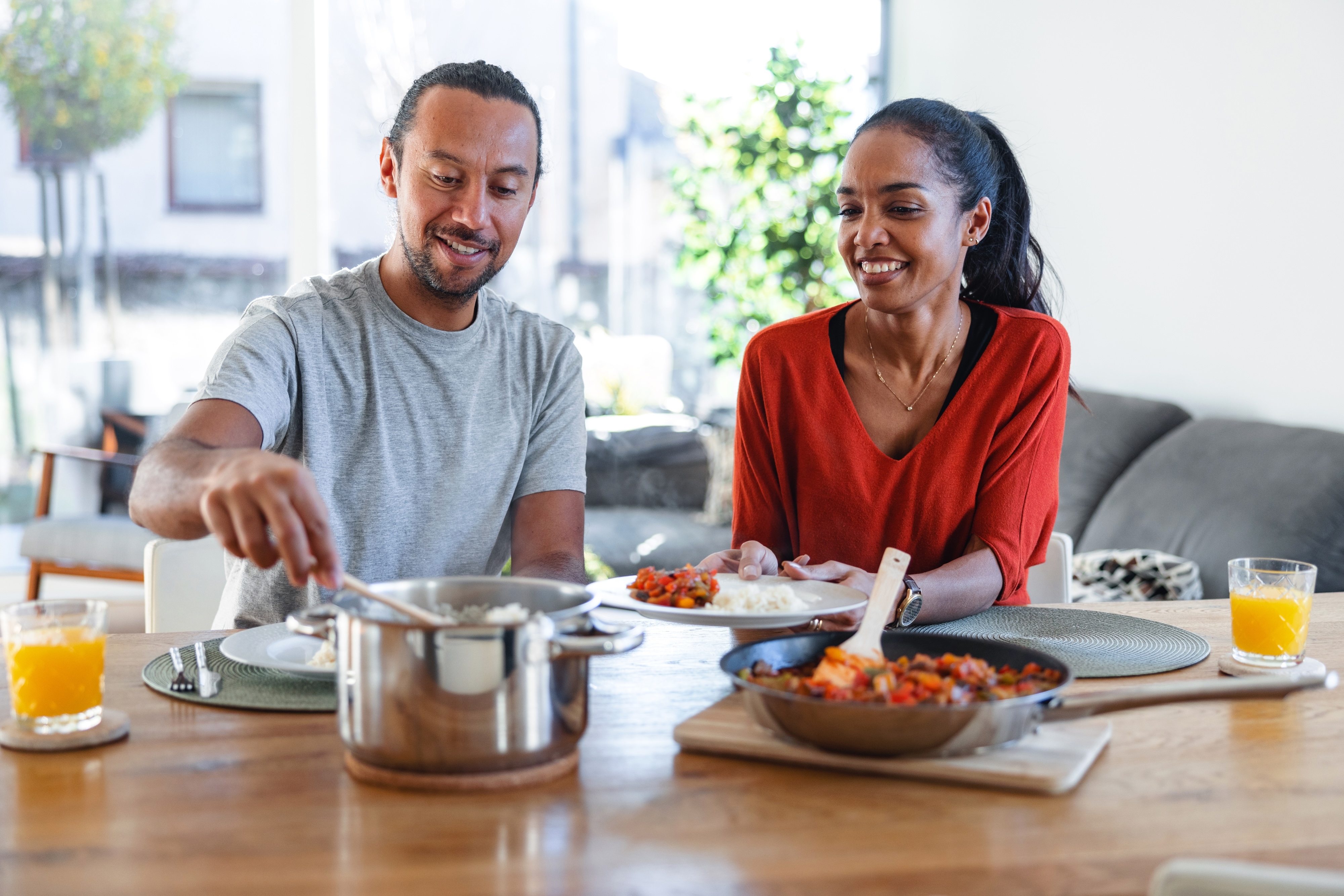 A couple eating a rice dish at their dinner table.