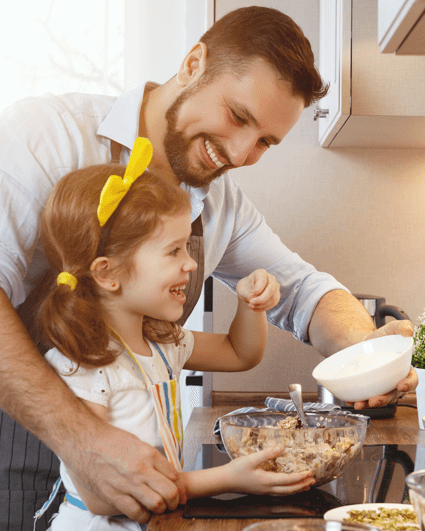 Father and daughter cooking together in the kitchen.