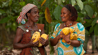 Two women smiling and holding cacao plants