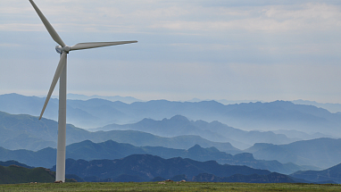 A windmill with rolling blue hills in the background