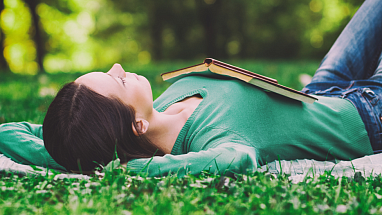 Woman lounging in the grass with a book