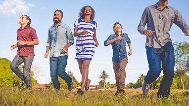Five happy people running in a field toward the camera