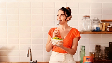 A woman smiles before eating a bowl of Ben's Original rice in her kitchen.