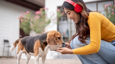 A woman feeding a dog from a bowl.
