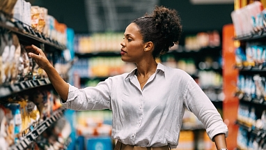 A woman looks at items in a grocery store aisle.