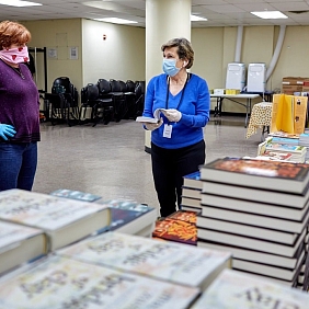 Two Mars Associates from AMERICAN HERITAGE® Chocolate wearing masks beside donated books.