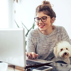 Woman on her computer accompanied by her dog.