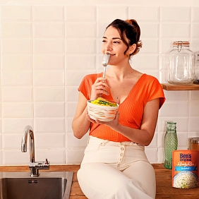 A woman smiles before eating a bowl of Ben's Original rice in her kitchen.