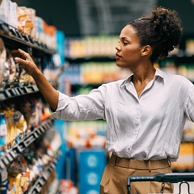 A woman looks at items in a grocery store aisle.