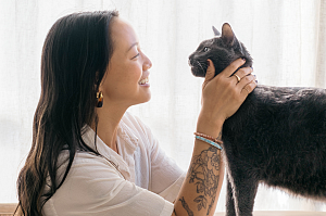 A woman smiling and petting a cat.