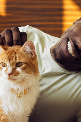 A man smiling and petting his cat